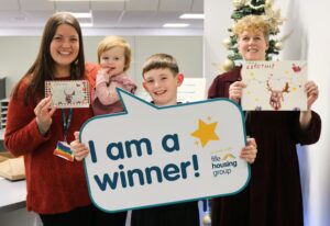 Ada and Arlo, winners of the children&rsquo;s Christmas card competition, standing with Fife Housing Group colleagues Melissa on the left and Carolyn on the right inside the office
